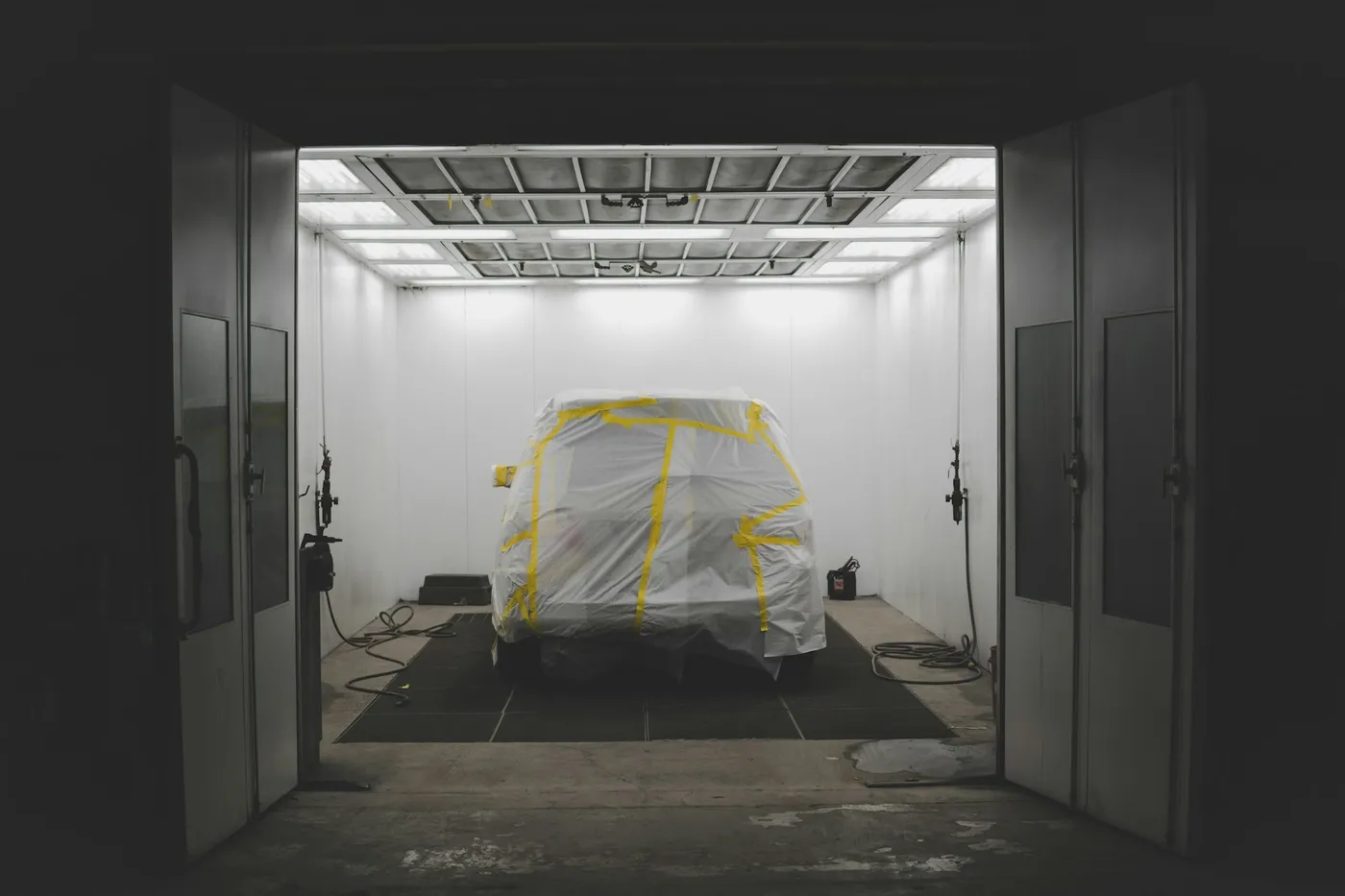 A car masked off and ready for paint in a paint booth